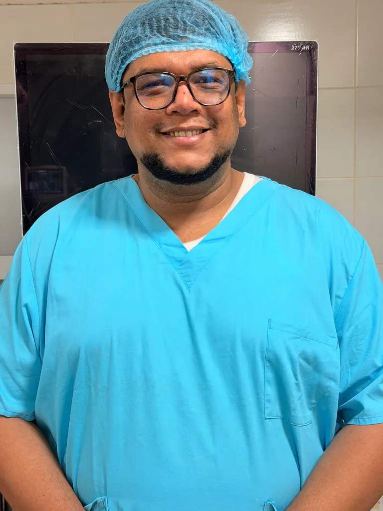 থিয়েটার স্ক্রাবে হাসিমুখে ডা. মারযূক — Dr. Marjuq smiling in theatre scrubs